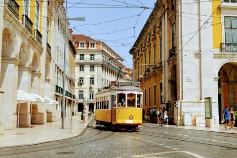 A yellow tram on a street of historic buildings in Lisbon